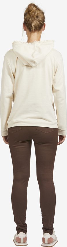Zicht op de rug van een zwangere vrouw in een off-white hoodie en bruine legging.