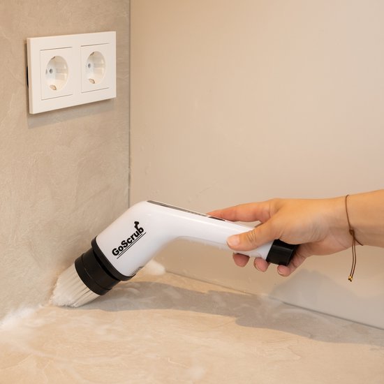Hand gebruikt de witte elektrische schrobborstel om een aanrecht schoon te maken.