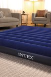 Close-up van een donkerblauw Intex luchtbed met ribbels op een wit tapijt.