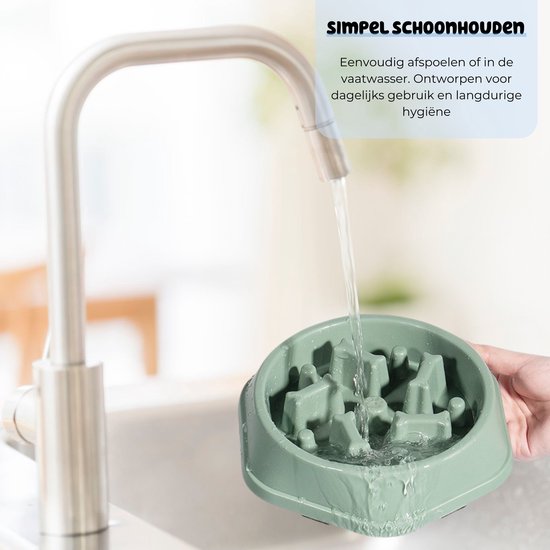 Een groene slowfeeder voerbak wordt onder de kraan afgespoeld.
