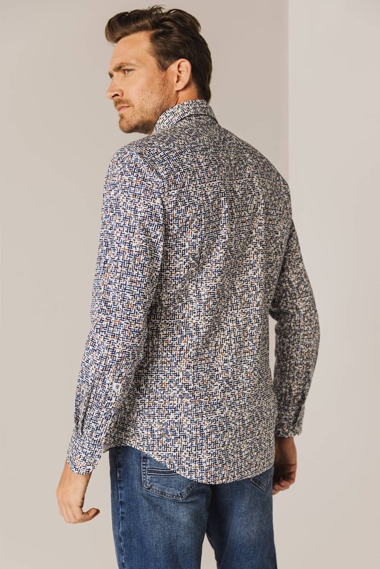Man met een blauw-wit met bruine print overhemd en spijkerbroek, staand van achteren.