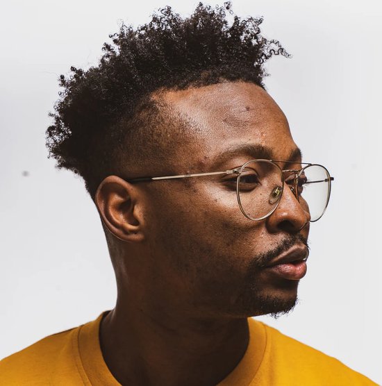 Portret van een man met een geel T-shirt en een bril, met gedefinieerde krullen.