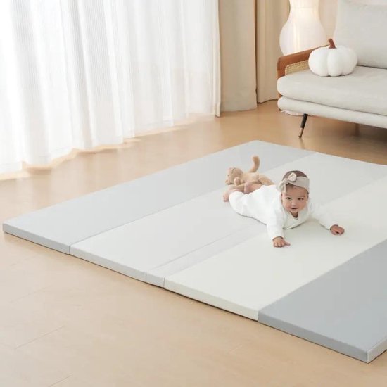 Baby kruipt op een grijze en witte gestreepte speelmat.