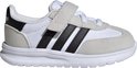 Witte kindersneaker met zwarte strepen en klittenbandsluiting.