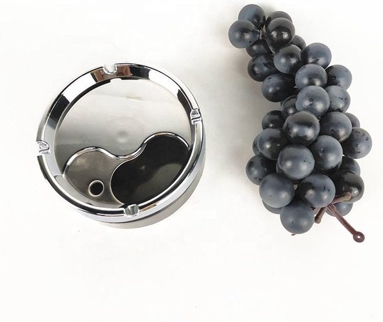 Zwarte draaiasbak met yin-yang motief en chroomkleurige rand, naast een tros donkerblauwe druiven.