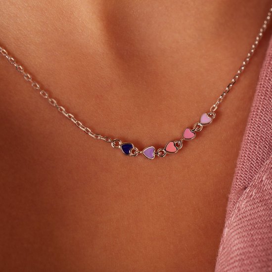 Zilverkleurige ketting met zes gekleurde emaille hartjes (paars, roze, donkerblauw) gedragen door een meisje.