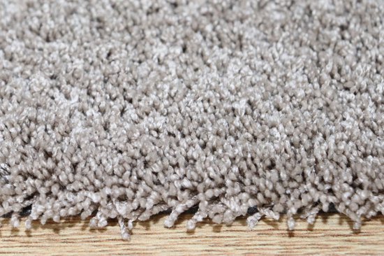Gros plan sur la texture douce et moelleuse d'un tapis de bain beige-taupe avec des franges en bas.