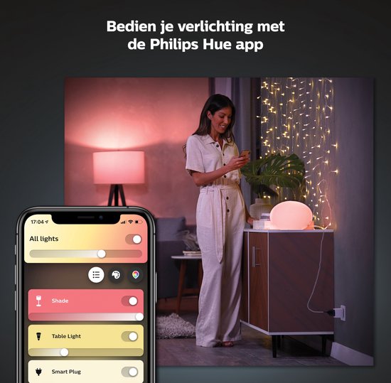 Vrouw met smartphone in een woonkamer met Philips Hue verlichting. Linkerhelft toont de Hue app.