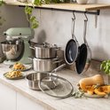 Een keukenblad met KitchenAid pannen, kookpotten, een mixer en pompoen.