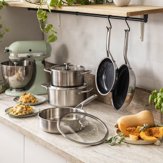 Een keukenblad met KitchenAid pannen, kookpotten, een mixer en pompoen.
