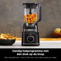 Zwarte Ninja blender met 2,1 liter kan gevuld met gehakte paprika en ui. Naast de blender staat een kom met tortillachips.