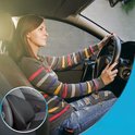 Vrouw met gestreepte trui en gescheurde jeans rijdt auto, met detail van autokussen.