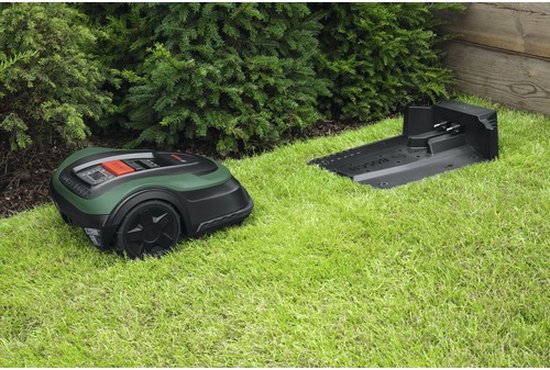 Bosch robotmaaier naast een laadstation op een groen gazon.