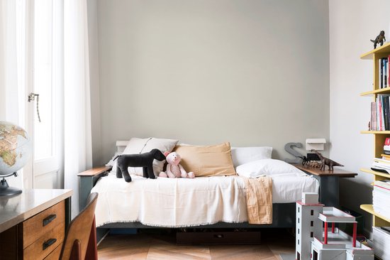 Kinderkamer met een bed, speelgoed, een wereldbol en gele opbergkast.