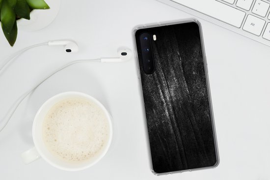 Een telefoonhoesje met zwarte metaalprint met glitter, op een bureau naast een kopje koffie en oortjes.