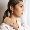 Model draagt een roségouden armband met hartvormig bedeltje bezet met kristallen.