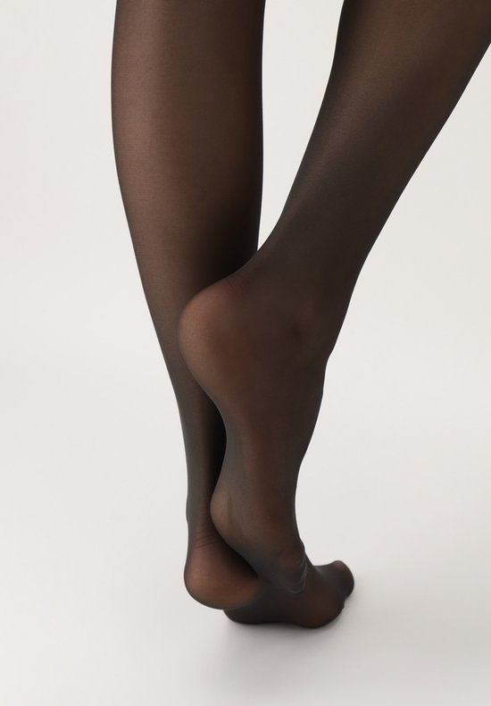 Een paar zwarte, doorschijnende panty's op blote voeten, met de hiel en tenen zichtbaar.