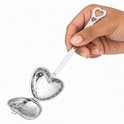 Hand die een zilverkleurig, hartvormig theefilter vasthoudt dat geopend is om te vullen.