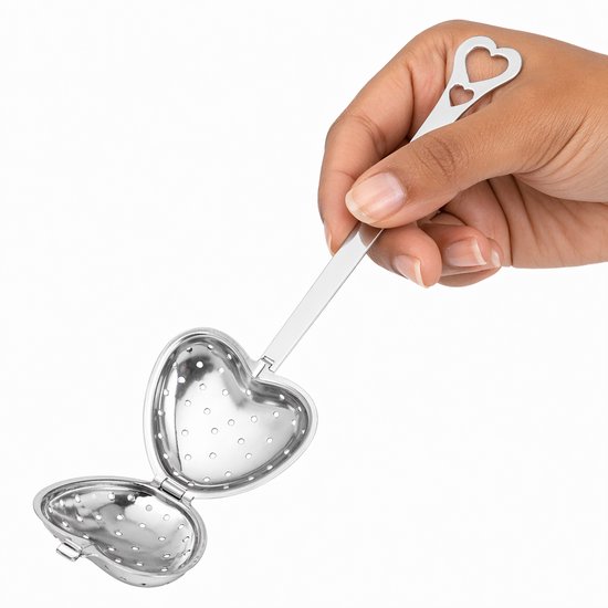 Hand die een zilverkleurig, hartvormig theefilter vasthoudt dat geopend is om te vullen.