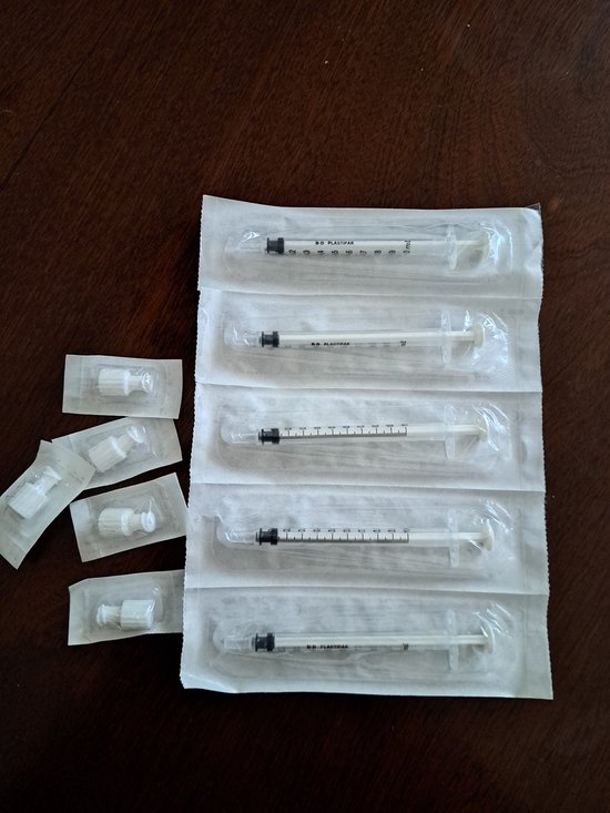 Vijf steriele 1ml BD Plastipak spuitjes in verpakking met dopjes.