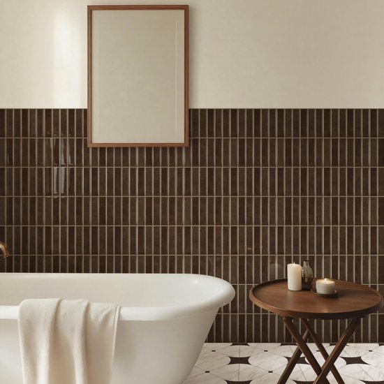 Badkamer met vrijstaand bad, bruine mozaïekwand en bijzettafel met kaarsen.