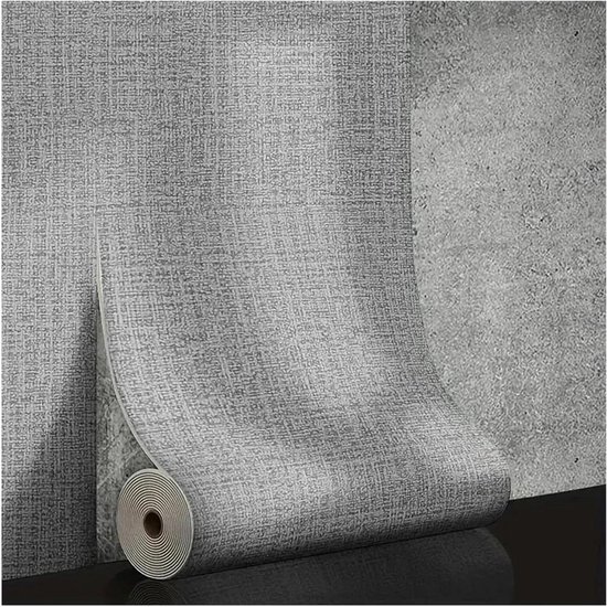 Papier peint gris texturé en rouleau contre un mur de béton.