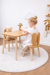 Houten kindertafel met twee stoeltjes met konijnenoren, een meisje speelt aan tafel.