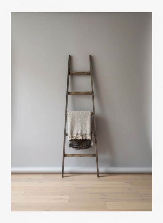 Een donkerhouten decoratieladder met een grijswitte gebreide plaid met franjes en een donkerbruine plaid erop.