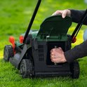 Groene Bosch grasmaaier met zwarte wielen, een persoon plaatst een onderdeel.