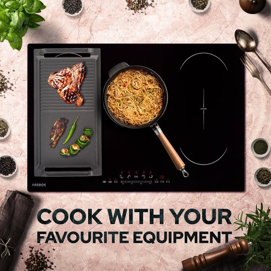 Zwarte grillplaat met T-bone steak, pepers en courgette op een inductiekookplaat met wok.