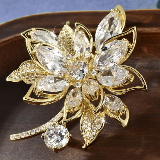 Gouden broche in bloemvorm met heldere, facetgeslepen stenen en kleine zirkonias.