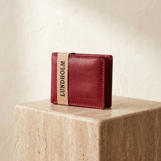 Lundholm portemonnee van rood leer, met band met "LUNDHOLM"-tekst, op een steen.
