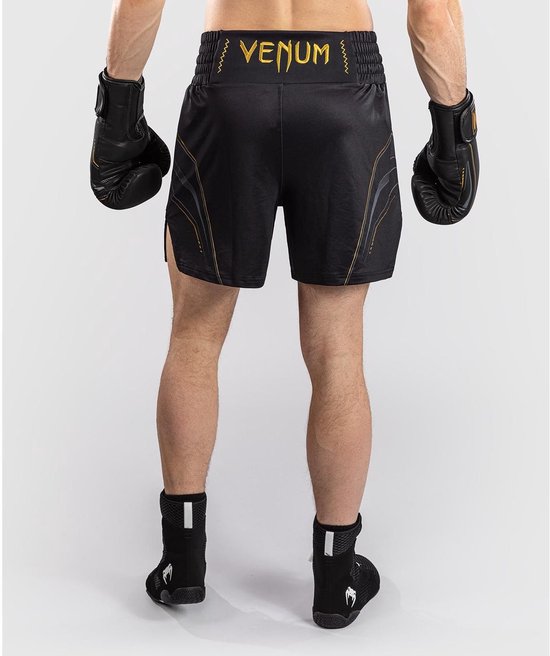 Zicht van achteren op een man in zwarte boksbroek met gouden VENUM-logo en gestileerde lijnen.
