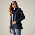 Vrouw met rood haar in een donkerblauwe, waterdichte jas, staand met de hand op de rits.