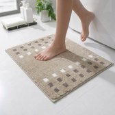 Een beige badmat met een patroon van bruine en witte vierkantjes. Een voet stapt op de mat bij een bad.