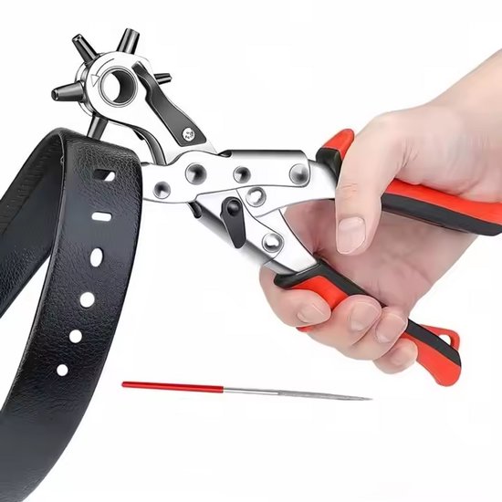 Een hand houdt een zilveren gaatjestang met rode handvatten vast om gaten in een zwarte riem te maken. Een metalen vijl ligt ernaast.
