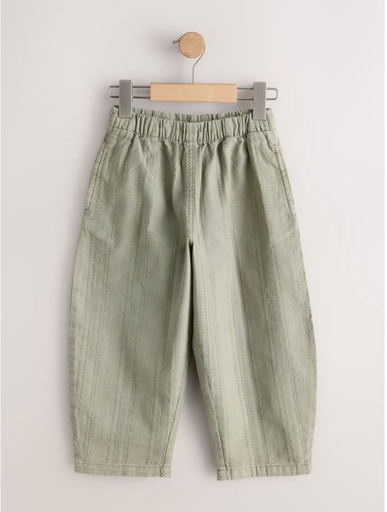 Lichtgroene broek met verticale ribbeltextuur en elastische tailleband.