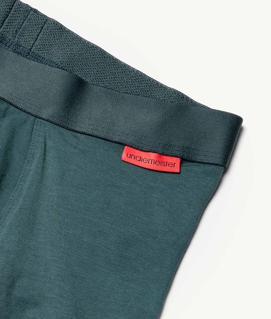 Close-up van de donkergroene tailleband van een boxeshort met rood Uniemeister label.