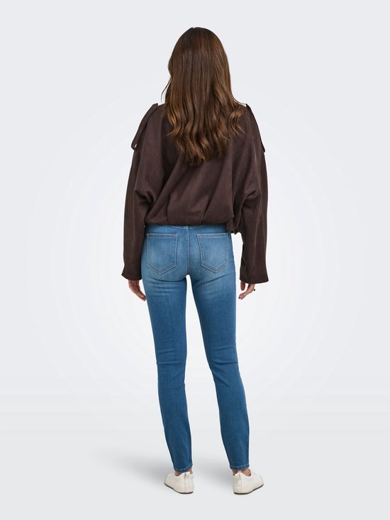 Achterkant van een model in een skinny jeans met hoge taille en een bruin jasje.