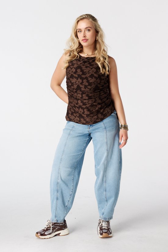Model van voren gezien, met een lichtblauwe balloon jeans en bruine top.