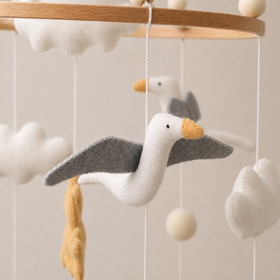 Vilten baby mobiel met vliegende meeuwen, wolken en ballen aan een houten ring.
