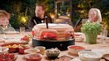 Een familie geniet van pizza's uit de oranje terracotta pizzarette, met diverse toppings op een tafel.