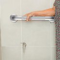Een zilveren muurbeugel met antislip handvat, gebruikt door een persoon met een bloemige jurk.