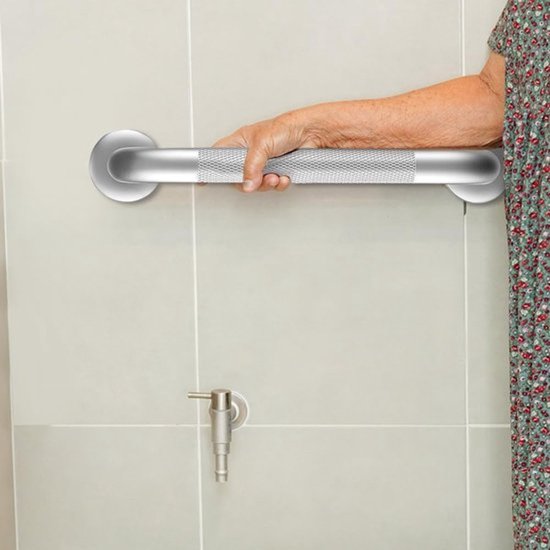 Een zilveren muurbeugel met antislip handvat, gebruikt door een persoon met een bloemige jurk.