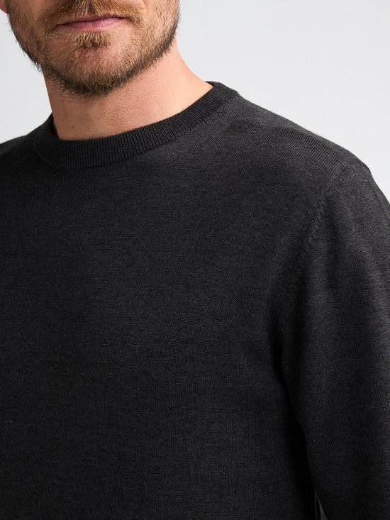 Close-up van de nek en schouder van een man die een donkergrijze gebreide trui met ronde hals draagt.