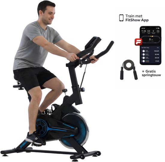 Man op een zwarte en blauwe spinfiets, met een springtouw en smartphone met trainingsapp ernaast.