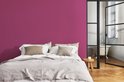 Een slaapkamer met een fuchsia muur, bed en ligbad.