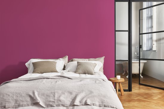 Een slaapkamer met een fuchsia muur, bed en ligbad.