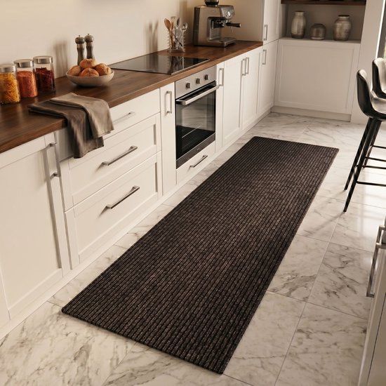 Tapis de cuisine brun rayé sur un sol en marbre clair, à côté d'armoires de cuisine blanches.