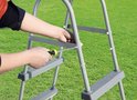 Handen monteren een grijze ladder met een schroevendraaier.